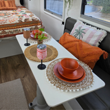 Vanaway caravan dining setup featuring Speckled Spice rPET dinnerware, insulated wine tumblers, and the Vanaway Reversed Sunblossom Throw Rug styled throughout a modern caravan interior. terracotta asymmetrical dinnerware