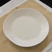 Overhead view of the Vanaway Speckled Coconut white rPET dinner plate on a natural linen table runner, showcasing the subtle grey speckled finish and modern lightweight design. asymmetrical dinnerware