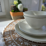 Close-up of the Vanaway Speckled Coconut rPET caravan dinnerware set, featuring stacked dinner plates, side plates and bowls with a soft white speckled finish. asymmetrical dinnerware
