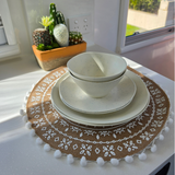 Speckled Coconut white rPET caravan dinnerware set including dinner plate, side plate and two bowls, styled on a woven boho placemat beside a cactus planter in natural sunlight. asymmetrical dinnerware