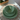 Top-down view of Vanaway Speckled Matcha rPET caravan dinnerware featuring a speckled sage green dinner plate, side plate and bowl stacked on a woven placemat with natural sunlight. asymmetrical dinnerware