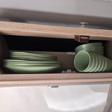Vanaway Speckled Matcha rPET caravan dinnerware neatly stacked inside an overhead caravan cupboard, showcasing the compact, space-saving storage of plates, bowls and tumblers. asymmetrical dinnerware