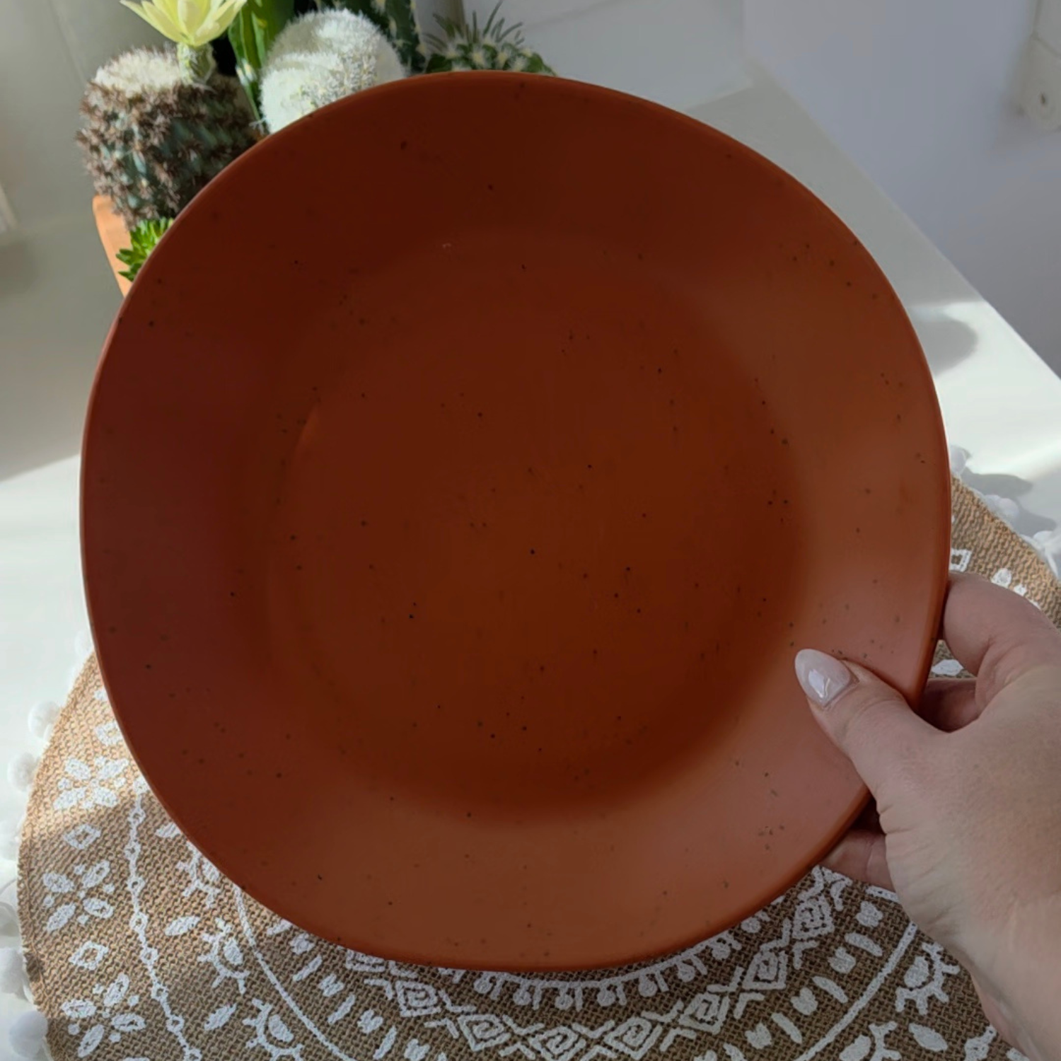 Vanaway Speckled Spice rPET caravan dinner plate held in hand, showcasing the warm terracotta colour, subtle speckled finish and generous size. asymmetrical dinnerware