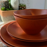 Close-up of the Vanaway Speckled Spice rPET caravan dinnerware set, featuring stacked dinner plates, side plates and bowls with a warm terracotta speckled finish. asymmetrical dinnerware