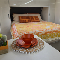Vanaway Speckled Spice rPET caravan dinnerware place setting displayed on a caravan table, with the Vanaway Solana Throw Rug styled across the bed in the background for a warm, coordinated camping interior. asymmetrical dinnerware