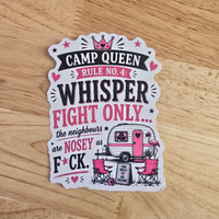 A die-cut sticker with a humorous camp queen slogan, displayed on a light wood grain surface. The sticker features a white background with pink and black text reading 'CAMP QUEEN RULE NO 4