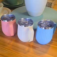 Three colorful insulated travel mugs on a wooden surface with a blurred background.