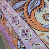 Close up of the Vanaway Dahlia woven travel throw rug border featuring pink and terracotta paisley details, decorative fringe and premium woven cotton texture.