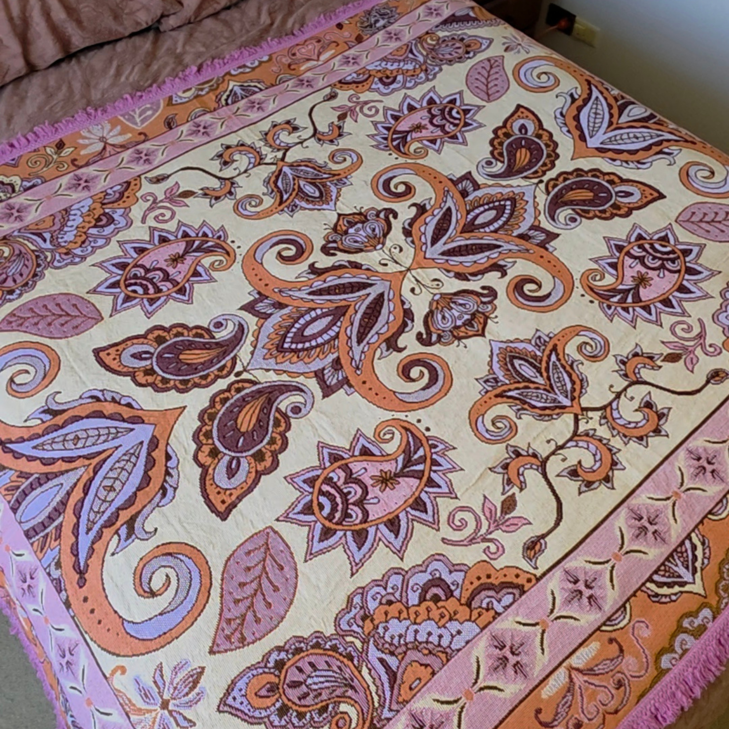 Close up of the Vanaway Dahlia woven travel throw rug showcasing its pink, lilac and terracotta paisley pattern with decorative fringe and premium woven texture.