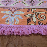 Close up of the Vanaway Dahlia woven travel throw rug showcasing its pink decorative fringe, terracotta border and premium woven cotton texture.