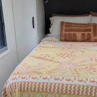 Vanaway Solana woven travel throw rug styled across a campervan bed, showcasing its mustard, blush and cream palm inspired design and premium woven cotton texture.