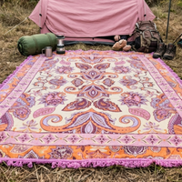 Vanaway Dahlia woven travel throw rug featuring a cream, lilac, lavender and terracotta boho paisley design, styled outside a tent with camping gear for comfortable outdoor adventures.