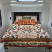 Vanaway Sahara woven travel throw rug featuring a cream, terracotta, sage green and blush boho botanical design, styled as a decorative bed throw inside a modern caravan.