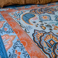 Close up of the Vanaway Santorini woven travel throw rug showcasing its soft blue, terracotta and cream boho paisley pattern with premium woven detailing.