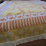 Close up of the Vanaway Solana woven travel throw rug showcasing its palm inspired border, decorative fringe and premium woven cotton texture in mustard, blush and cream.