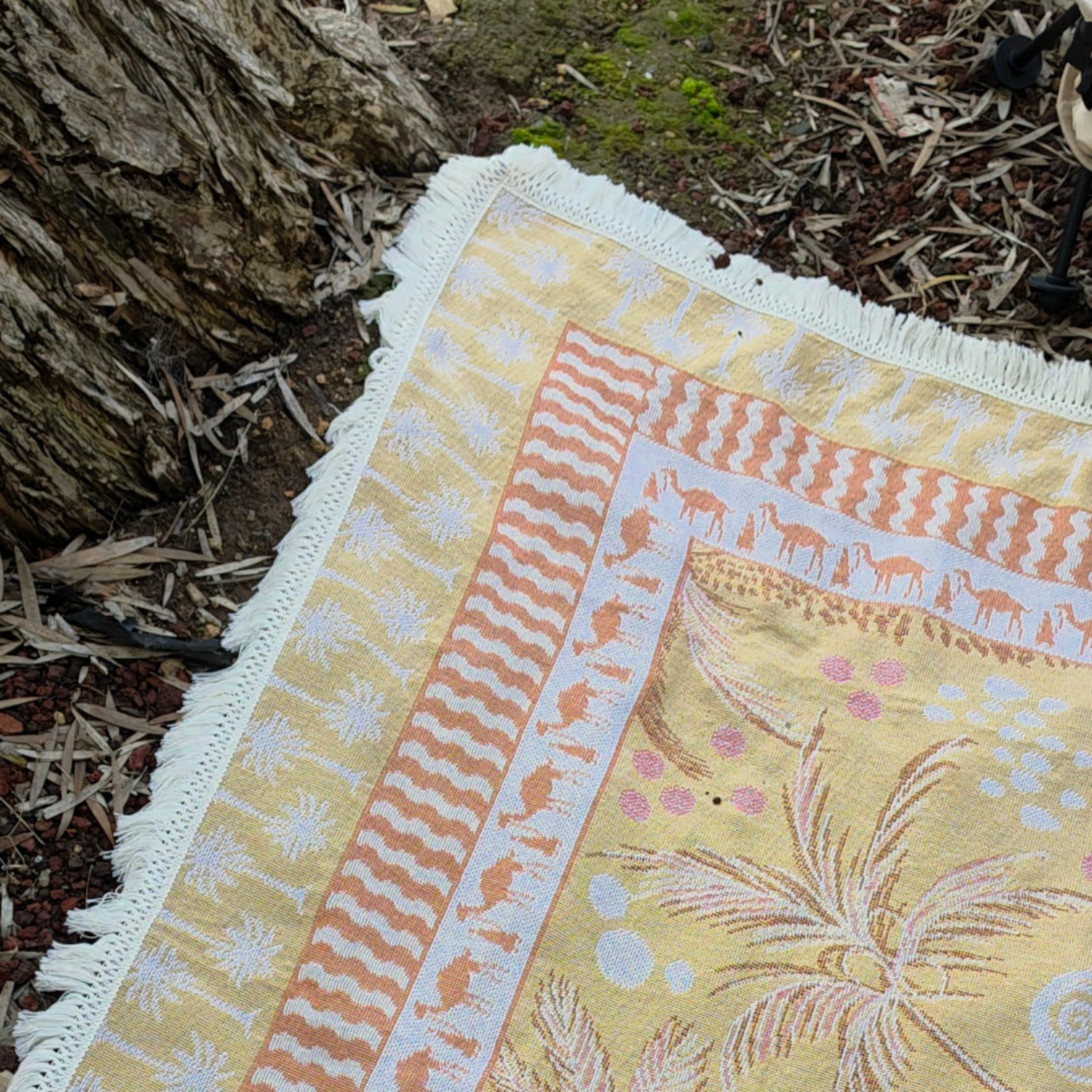 Close up of the Vanaway Solana woven travel throw rug corner showcasing its mustard, blush and cream palm inspired border, decorative fringe and premium woven cotton texture.