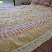 Close up of the Vanaway Solana woven travel throw rug showcasing its mustard, blush and cream palm inspired border, decorative fringe and premium woven cotton texture.