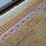 Close up of the Vanaway Solana woven travel throw rug showcasing its palm, camel and geometric border pattern with premium woven cotton texture in mustard, blush and cream.