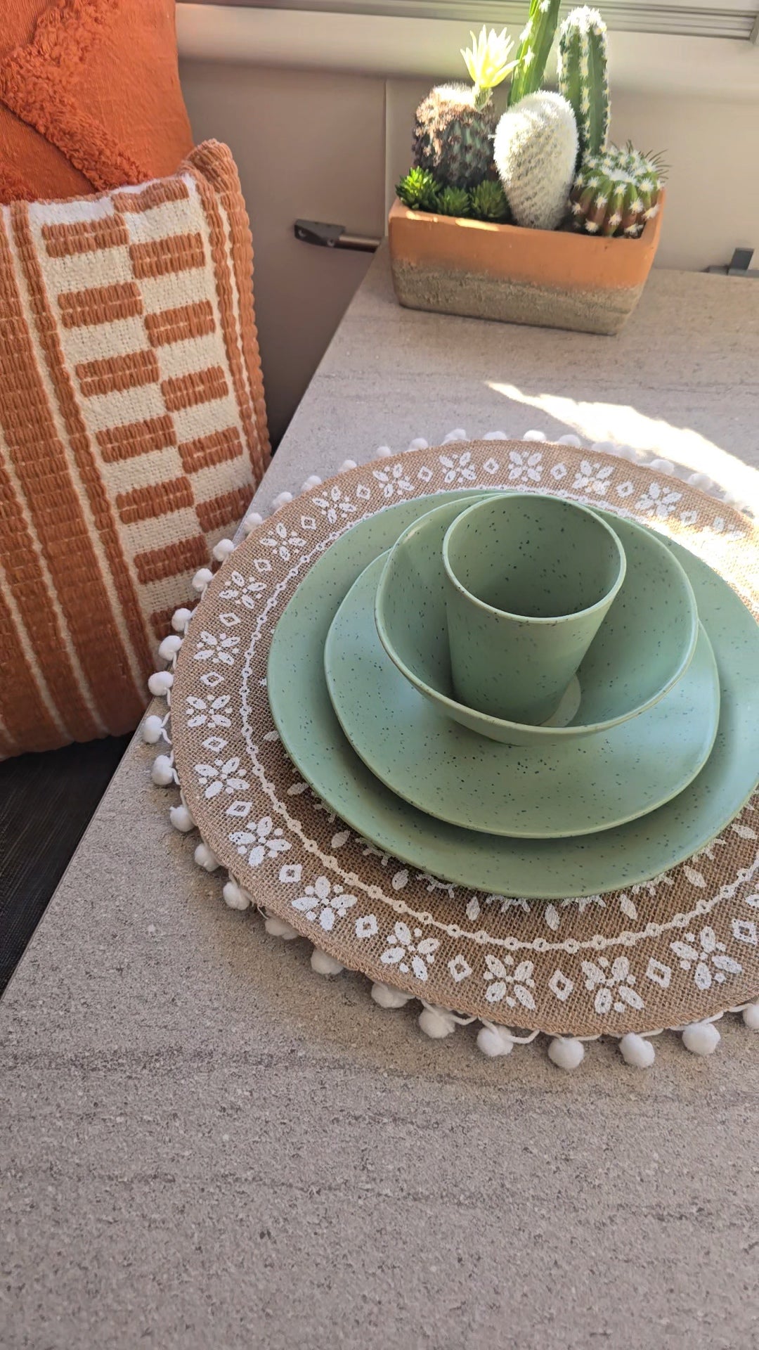 Vanaway Speckled Matcha recycled plastic camping dinnerware with a dinner plate, side plate, bowl and tumbler in a soft sage green speckled finish, styled inside a caravan.