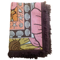 Folded Vanaway Sunblossom woven travel throw rug, showcasing the floral design, woven texture and soft fringe edges.