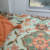 Vanaway Willow woven travel throw rug featuring soft blue, sage green, cream and terracotta botanical patterns, styled as a decorative bed throw inside a modern caravan.