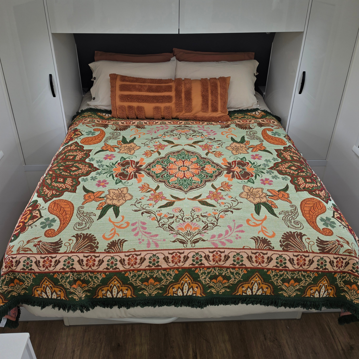 Vanaway Willow woven travel throw rug featuring soft blue, sage green, cream and terracotta botanical patterns, styled as a decorative bed throw inside a modern caravan.