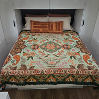 Vanaway Willow woven travel throw rug featuring soft blue, sage green, cream and terracotta botanical patterns, styled as a decorative bed throw inside a modern caravan.