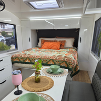 Vanaway Willow woven travel throw rug featuring soft blue, sage green, cream and terracotta botanical patterns, styled inside a modern caravan with matching camping dinnerware and insulated drinkware.